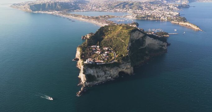 Aerial view of the island in Capo Miseno featuring white cliffs, lush greenery, and buildings contrasting against the deep blue sea, Capo Miseno, Campania, Italy.