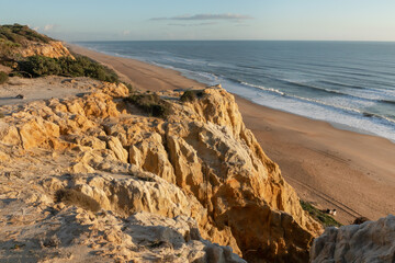 Scenic Atlantic coastline with golden cliffs, sand dunes and empty beach at Donana, El Arenosillo, Mazagon, Huelva, Spain. Natural landscape, travel and nature concept.