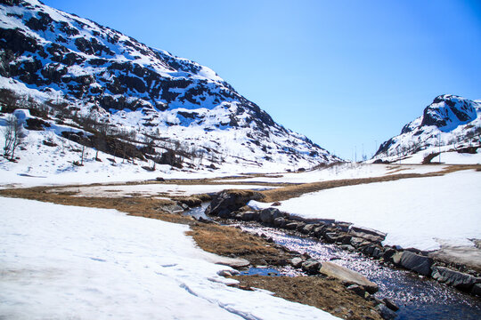 Schneetal mit Bach in norwegischen Bergen