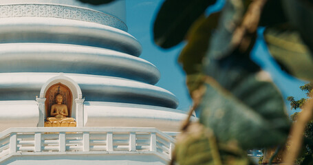 Buddha statue in temple niche with blue and white dome architecture at Rumassala Peace Pagoda