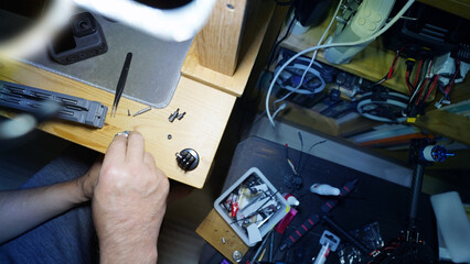Close-up of a technician’s hands repairing machinery with tools and components.