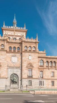 Panorama showing Cavalry Academy facade timelapse in Plaza de Zorrilla, Valladolid, Spain. Historic military building with intricate architecture, surrounded by busy urban scene under blue cloudy sky