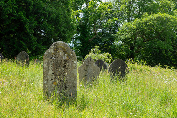 Brockenhurst, UK - May 31st 2025: Gravestones in the long grass in St Nicholas&rsquo; Churchyard.