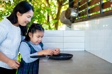 Close up hands using chopsticks to eat Thai BBQ or Moo Kata. Grilled pork on hot brass pan with steam and vegetable soup. People enjoying traditional Asian buffet meal in restaurant.