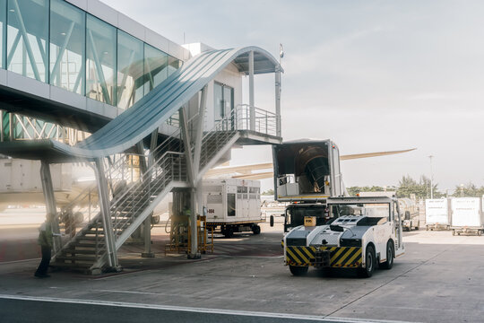 Phuket, Thailand, January 6, 2026: Airport is a tow truck for towing ships and a telescopic ramp connecting terminal building with an airplane for boarding or disembarking passengers. ground services