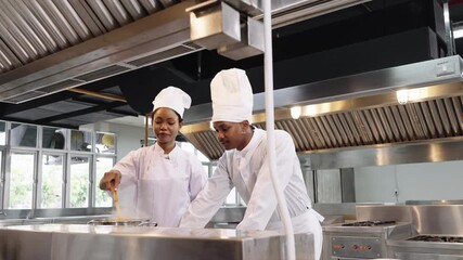 Two African American chefs discussing recipes while walking through professional restaurant kitchen, showing teamwork, friendship and culinary.