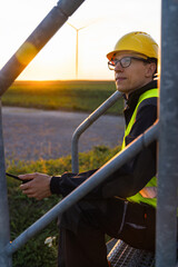 Engineer with digital tablet works on a field of wind turbines