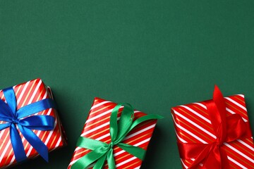 Top view of beautiful Christmas gift boxes with ribbons on green background