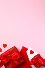 Beautiful gift boxes with red hearts and paper envelope on pink background