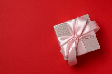 Festive gift box with pink bow on red background. 