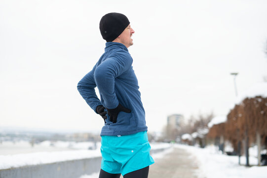 Runner experiencing lower back pain during winter exercise