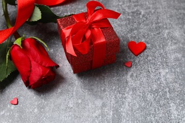 Beautiful red roses, gift box and hearts on gray background