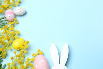 Colorful Easter eggs, bunny ears, decorations and vibrant spring flowers on yellow. Easter celebrations, and the freshness of spring festivities