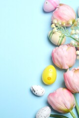 Happy Easter. Top view photo of tulips and multicolored eggs on pastel blue canvas, with empty space for text