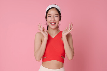 Fitness lifestyle portrait smiling Asian woman in activewear standing confidently healthy body concept workout motivation wellness and self care modern sport fashion studio pink background.