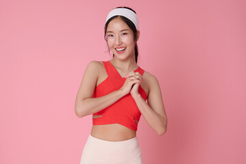 Fitness lifestyle portrait smiling Asian woman in activewear standing confidently healthy body concept workout motivation wellness and self care modern sport fashion studio pink background.