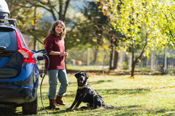 Woman with her dog next to charging electric car