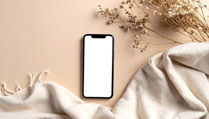 A minimalistic composition featuring a blank smartphone on a soft fabric with dried flowers