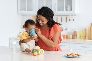 Adorable Little Baby Boy Drinking From Mother's Cup While Spending Time Together In Kitchen, Enjoying Tasty Drink, Happy African American Family Mom And Infant Child Relaxing Together At Home