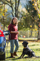 Woman with her dog next to charging electric car