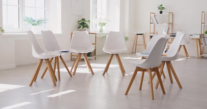 Chairs circle set up in empty office room interior before meeting, support therapy and group discussion. Modern white wooden seats waiting waiting for training session and workshop participants
