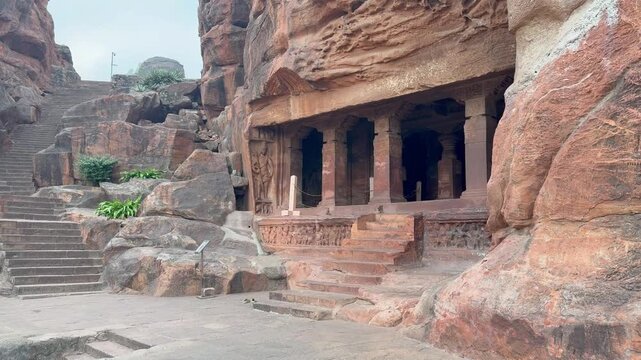 A beautiful view of Badami Cave Temple No. 1, showcasing the ascending stone steps carved into the cliff and the striking red sandstone rock, reflecting the timeless charm of Chalukyan architecture