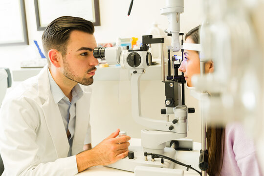 Hispanic ophthalmologist examining patient's vision with a slit lamp during a comprehensive eye health checkup at the clinic