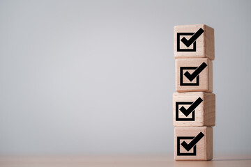 Stack of wooden blocks with check mark icons representing completed checklist, approval process of...