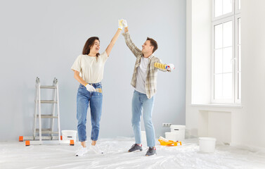 Happy young married couple enjoying home renovation fun, repair after moving into new house,...