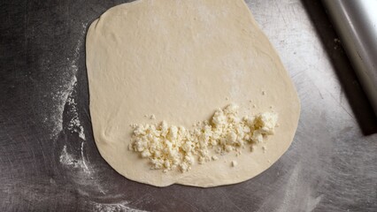 Chef in black gloves rolling pizza dough with rolling pin