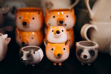 Close-up of cute ceramic cups shaped like animals displayed on a shelf.