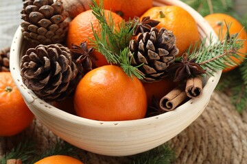 Ripe tangerines, spices, cones and fir tree branches on table, closeup