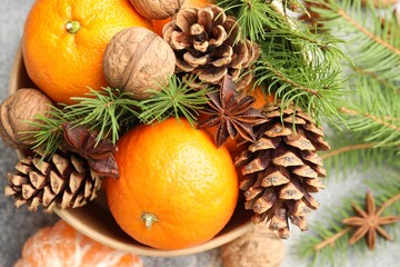 Fototapeta premium Tangerines with cones, anise stars and fir tree branches on grey table, flat lay