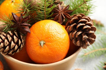 Tangerines with cones, anise stars and fir tree branches on grey table, closeup