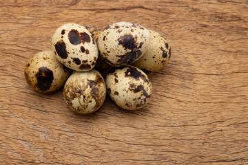 Obraz premium A group of small organic spotted quail eggs lies on a rustic wooden table background as a healthy raw gourmet ingredient for a high protein breakfast