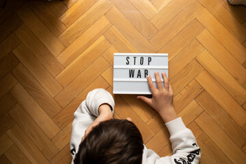 Child holding stop war message with copy space