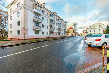 White multi-story residential building with red roof behind green lawn