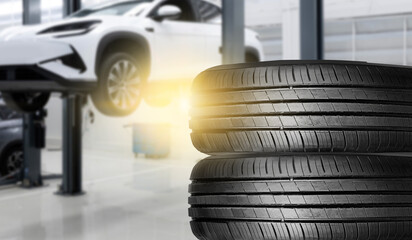 Car wheel service with tires stacked and vehicle lifted in auto shop.