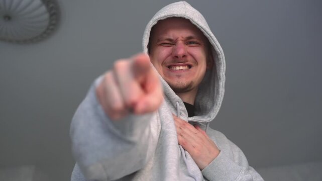 An adult man mocks and humiliates someone.
Mocking and bullying.
A man points at a person and laughs at them.