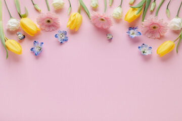 Bouquet of beautiful spring flowers on pastel pink table top view. Greeting card for International Women Day or Mother day. Flat lay.