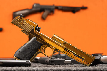 Profile of a luxury gold plated semi automatic handgun with open slide mechanism lying on a table...