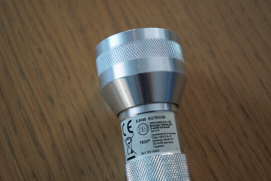 Close-up of a silver metal flashlight with textured grip on a wooden surface