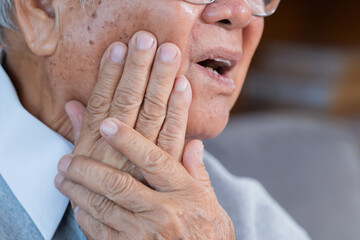 Elderly man grab his cheek suffer from toothache at home