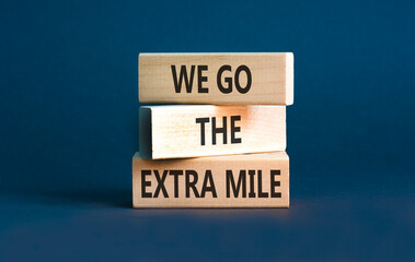 Support, help we go the extra mile symbol. Concept words We go the extra mile on beautiful wooden blocks. Beautiful grey background. Business we go the extra mile concept. Copy space.