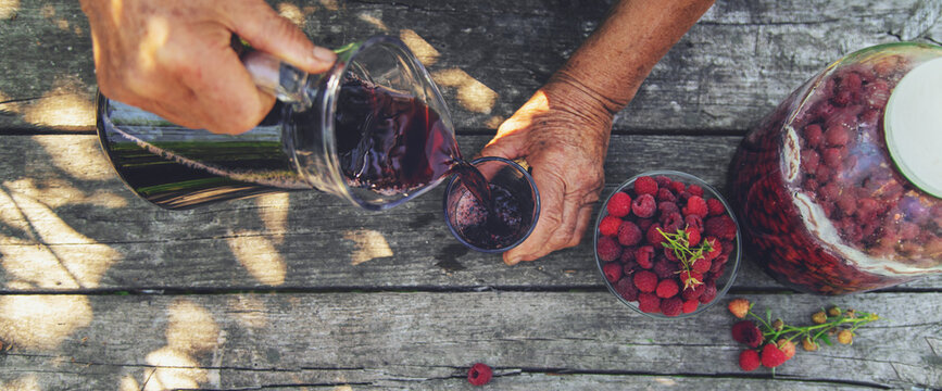 Grandma makes wine from raspberries in the garden. Selective focus.