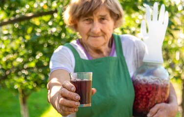 Fototapeta premium Grandma makes wine from raspberries in the garden. Selective focus.