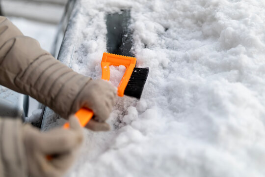 Person scraping snow and ice from car windshield