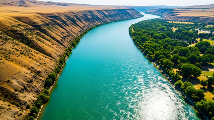 Fototapeta premium aerial view of a vibrant turquoise river flowing through a contrasting arid canyon landscape meeting a lush green valley for travel and environmental themes