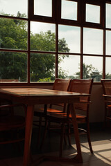 Obraz premium Set up a vintage wooden cafe table with a glass room and a view of green trees