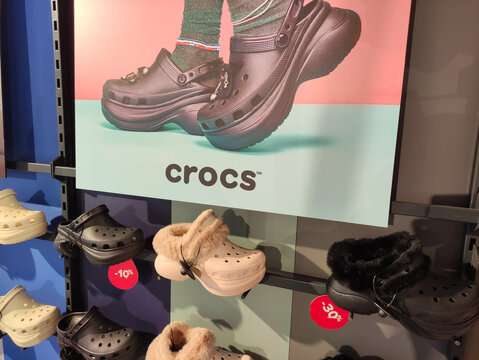 Rome, Italy - January 14, 2026: Crocs footwear display featuring black clogs and fuzzy-lined shoes on a colorful retail shelf with promotional price tags visible